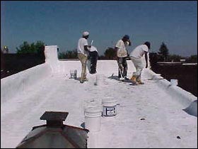 Workers apply a cool roof coating on a rowhouse in Baltimore, MD