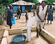 A Haitian woman enjoys the ease and cleanliness of an improved potable water source in Mont Organisé (a rural village), with support from USAID.