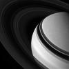 Held in gravity's embrace, Saturn's darkened, icy rings encircle the clouded gas giant