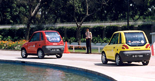 Two REVA cars circle the pond in front of the 
U.S. Embassy in New Delhi. Photo Credit: USAID India