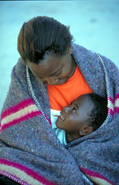 A mother and her child enjoy the warmth of blanket donated by USAID Zambia programs. Photo: Jon Warren/World Vision.