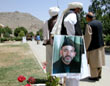 Photo: Delegates stand next to a political poster for Hamid Karzai.