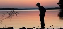 Kid silouted against sunset in front of lake