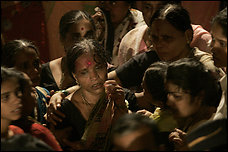 The wife of Balasaheb Bhosale cries at his funeral in Mumbai. Her face is red with ink from her bindi, the decorative mark on her forehead. Balasaheb Bhosale was a police official who died while trying to stop gunmen at a railway station in India's commercial capital. Black-clad Indian commandoes raided two luxury hotels as they attempted to free hostages from the gunmen, and explosions shook the city, which seemed staggered by grief. Story, A15.