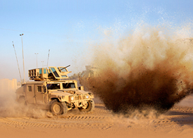 An improvised explosive devise explodes next to a humvee.
