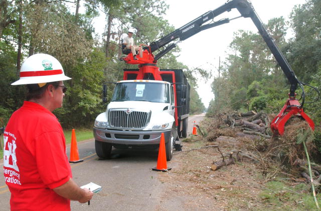 A Army Corps emergency operations employee looks on while a fellow employee operates a backhoe to remove debris from a roadway after Hurricane Katrina.(Photo White House)