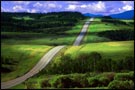 A country road climbs through rolling green hills