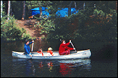 Photo of two adults and two children in a canoe on the water