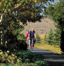 View of a sunny bike path with a couple bicycling