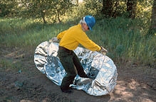 Picture of a man setting up a fire shelter.