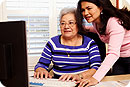 A grandmother and adult daughter using a computer.