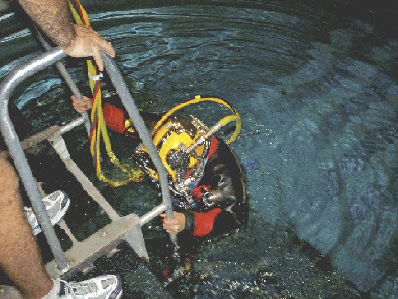 A diver wearing the Paragon suit descends a ladder into the water. 