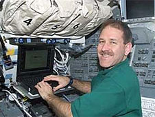 Astronaut John Grunsfeld types on a laptop computer