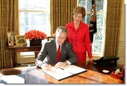 With Laura Bush looking on, President George W. Bush signs a proclamation designating February as American Heart Month in the Oval Office, Feb. 1, 2005. The proclamation encourages awareness of factors leading to heart disease such as smoking, high cholesterol, lack of exercise, obesity and diabetes.  White House photo by Susan Sterner