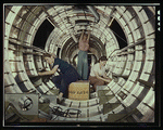 Women workers install fixtures and assemblies to a tail fuselage section of a B-17 bomber