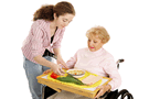 Image of a preteen assisting an elderly woman in the wheelchair with her meal