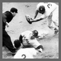 A baseball player sliding into base as another player attempts to tag him.