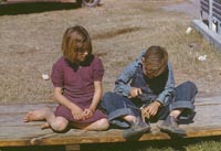 Boy building a model airplane as girl watches