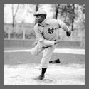 A baseball player following through after throwing a ball.