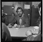 Unidentified man, half-length portrait, facing front, playing cards with other coke workers in Ruhr, West Germany
