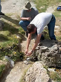 Photo: a man cracking an egg into a small stream.