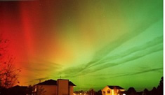 Reds, yellows and greens light up the sky  over some houses.