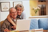 Photo of a couple using a laptop computer in their home.