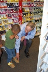 Senator Carper helps a young boy pick out some boots for the winter.