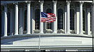 Photo of an American Flag flying above the US Capitol Building.