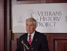 Senator Lugar standing in front of a Veterans History Project banner.