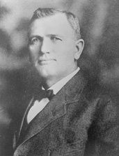 A black and white photo of Senator Hom O. Bursum, who is wearnig a dark jacket, white shirt, and bowtie.