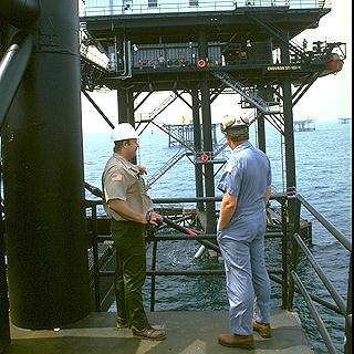 Inspectors on an offshore oil platform looking towards other offshore oil platforms.