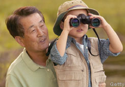 Boy looking through binoculars with father