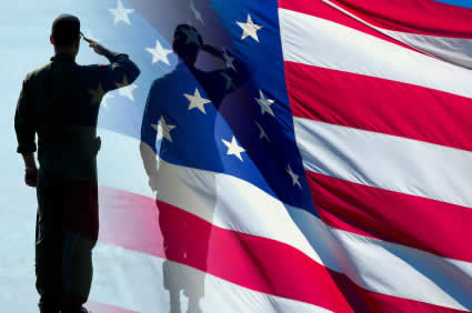 A soldier standing and soluting in front of a background of the American Flag