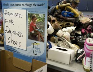 Desk with pile of shoes and sign asking for more (AP Images)
