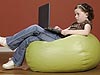 Young girl on a beanbag looking at a laptop computer on her lap