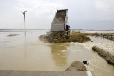 Oakville, Iowa, July 6th, 2008 -- A truck dumps a load of rock into a levee breech as the U.S. Army Corps of Engineers works to repair a road to i...