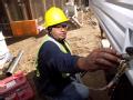 Delzura, CA, December 5, 2007 -- Jaime Castro, of J & J Plumbing, Inc. installs a water facet outside the mobile home a family will temporarily li...