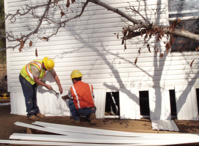 Delzura, CA, December 6, 2007 -- Contractors from Greg Wanket Construction install the skirting of a FEMA-provided mobile home to prepare it for o...