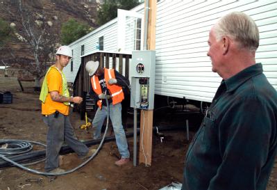 Delzura, CA, December 5, 2007 -- FEMA applicant Jon Grice, right, watches as electricians Adam Murschel, left, and Franklin wood, both of O'Donnel...