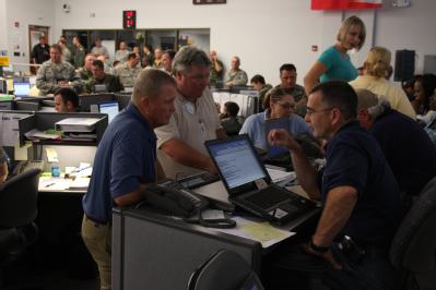 Baton Rouge, LA, September 3, 2008 -- FEMA employees in the EOC, group together to discuss events taking place throughout the day, during disaster...