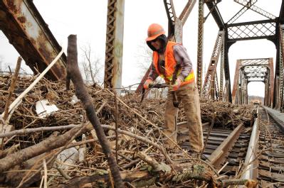 Valley Park, MO, March 23, 2008 -- A railroad worker removing debris from the tracks on a  railroad bridge passing over the Meramec River.  The de...