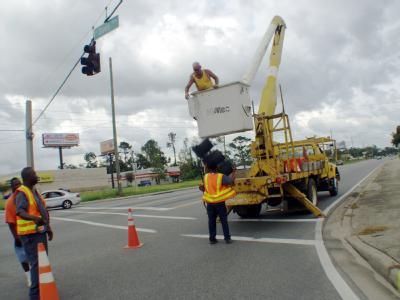 Pensacola, Fl. August 28, 2005. - Maintenance workers in the City of Pensacola remove a hanging street light to prevent damage from the expected h...
