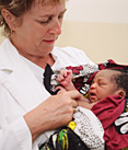 A medical volunteer with Cross-Cultural Solutions cares for a baby with HIV/AIDS at a health clinic in Arusha, Tanzania.