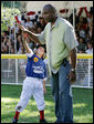 A player for the Stars reaches up to give a high-five to former New York Yankees All-Star player Bernie Williams, the first base coach at the Tee Ball on the South Lawn: A Salute to the Troops game between the Stars and Stripes, Sunday, Sept. 7, 2008, played by the children of active-duty military personnel. White House photo by Chris Greenberg