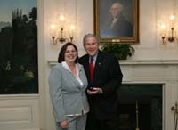 President Bush presents the President's Volunteer Service Award to Coast Guard spouse Ramona Vazquez from Baltimore, Maryland, before the White House celebration of  Military Spouse Day on Tuesday, May 6, 2008.  Vazquez is the President of the Greater Baltimore Area Coast Guard Spouses Association.  She is the creator and webmaster of the Coast Guard Spouses Association website, an online resource for new families transitioning into the Baltimore area.  Vazquez is also the founder of Nate’s Open Door Baby Pantry, which provides diapers, formula, clothing, toys, and furniture at no cost to military members of all ranks and services and civilians.  The program was named in honor of DC3 Nathan Bruckenthal, who was killed in action in 2004 while serving a second tour in Iraq.  Nate and his wife were expecting their first child at the time of his death.  In addition, Vazquez has adopted two soldiers and their platoons through Soldier’s Angels, a nationwide program that enlists volunteers to aid and assist deployed soldiers all over the world through care packages and letters of encouragement.