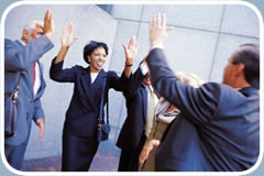 Several men and women dressed in business attire exchange “high fives.”