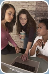 Three women discuss a project and look up information on a laptop computer.