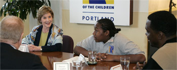 Photo of Mrs. Laura Bush sitting at a large conference table with members of "Friends of the Children."