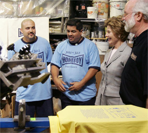 Photo of Mrs. Laura Bush and Homeboy Industries staff standing in the Homeboy Industries factory next to silk-screening equipment.